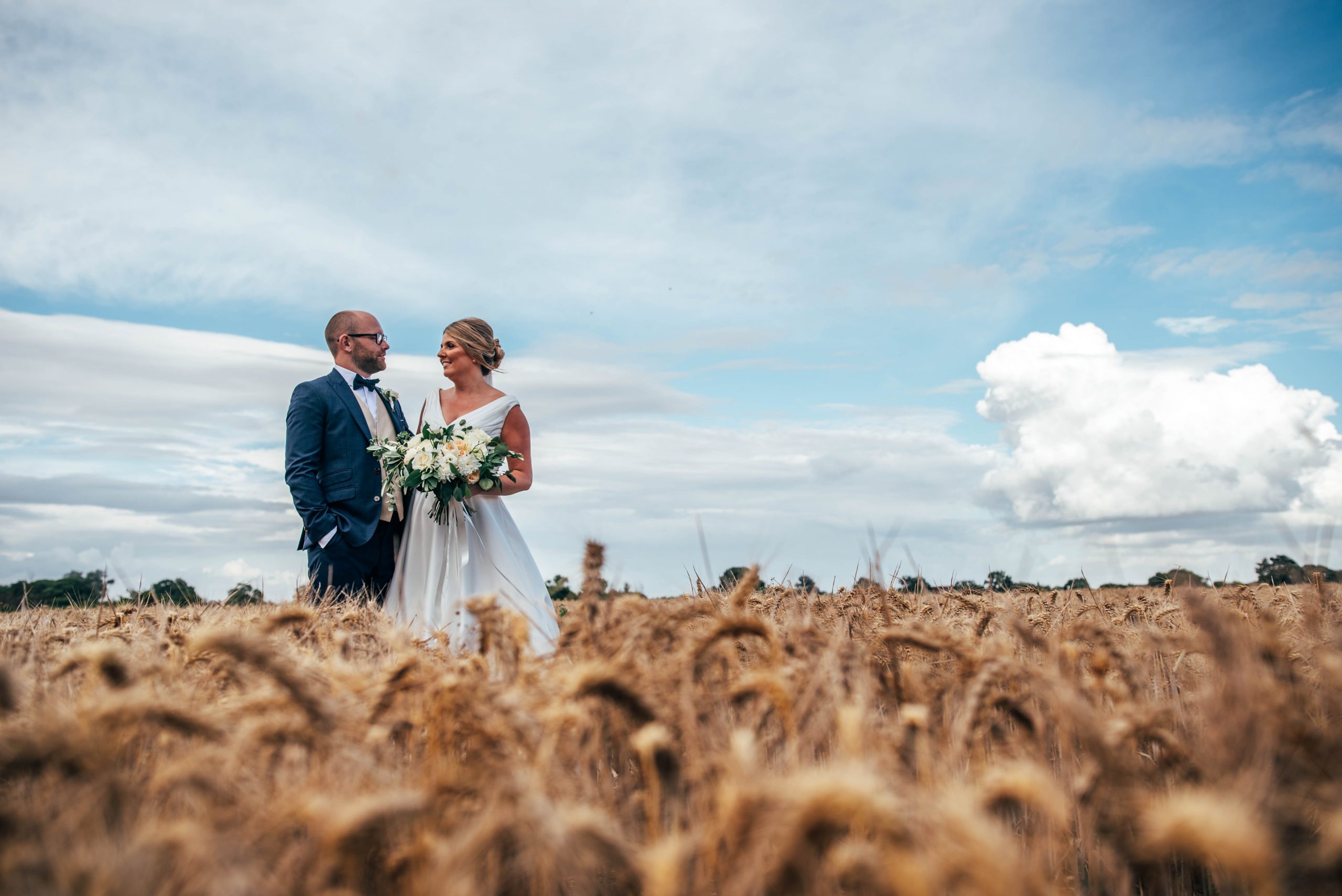 Bride and groom stand together in wheat field at Vaulty Manor