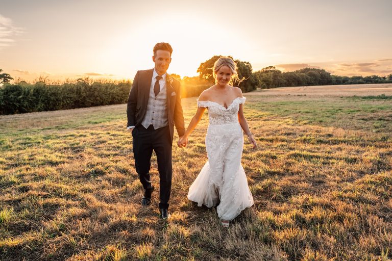 Bride and groom walk around sunset in grounds at Villiers Barn
