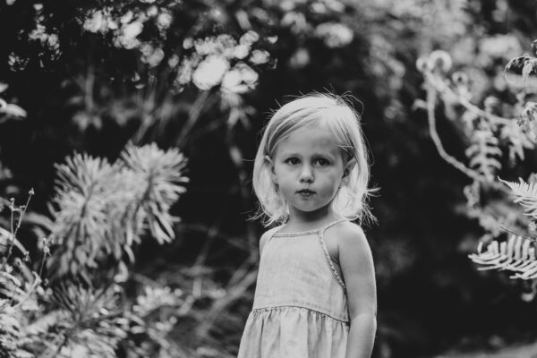 little girl stands amongst plants at Hylands Park Essex family lifestyle childhood baby photographer