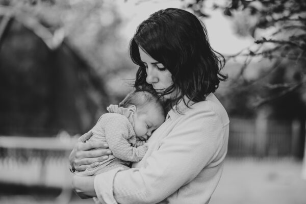 mum holds newborn baby girl in her garden Essex lifestyle family baby childhood photographer