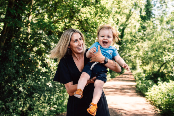 Mum holds her laughing toddler son in the air Essex family lifestyle baby childhood photographer