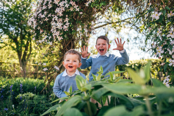 two little boys smile at camera in back garden on sunny day Essex lifestyle baby family childhood photographer