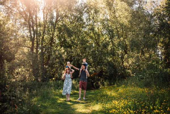 family of four walk in sun lit field Essex family lifestyle baby childhood photographer