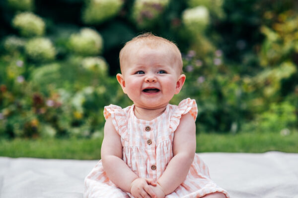 baby girl sits and laughs in park Essex lifestyle family baby childhood photographer