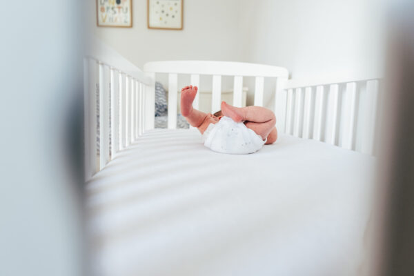 baby's feet in his crib through the bars at home in his nursery Essex family newborn baby portrait childhood photographer