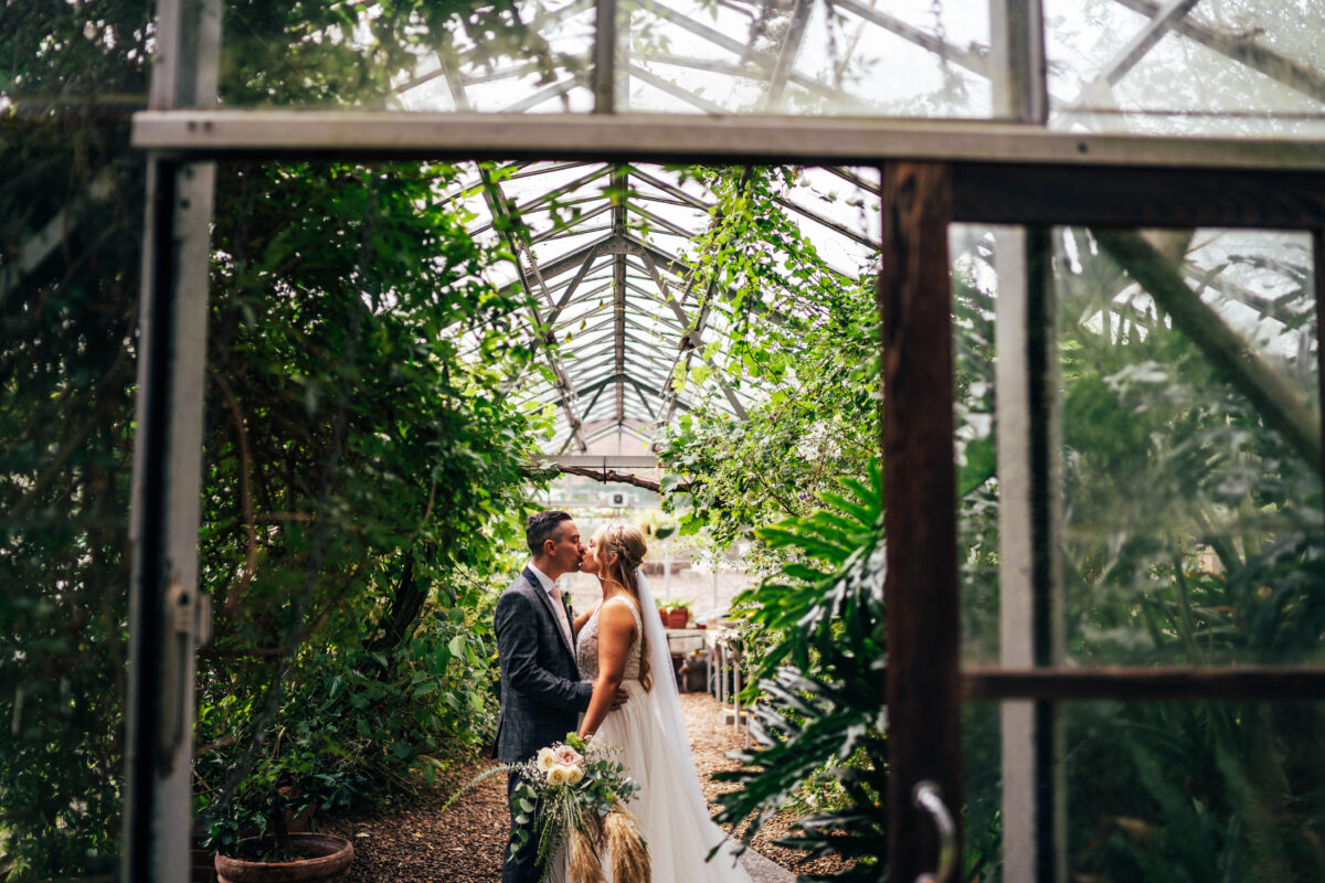 Bride and groom kiss in a greenhouse at Nettlested Best Essex Kent documentary wedding photographer