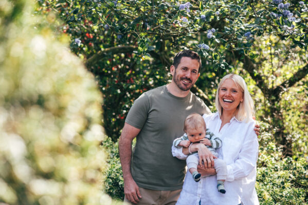 Family of three laugh in a park Essex lifestyle family baby childhood photographer