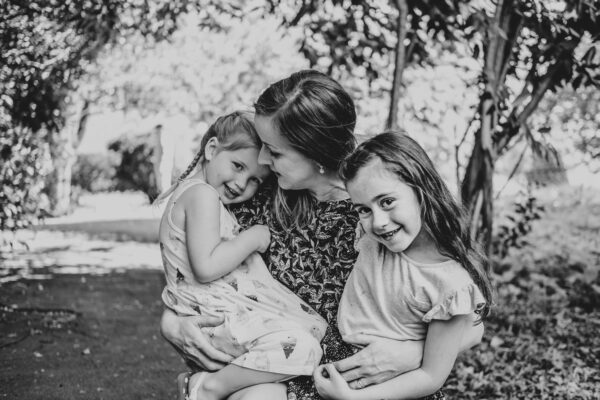 Mum holds both daughters as they look at camera Essex family lifestyle baby childhood photographer