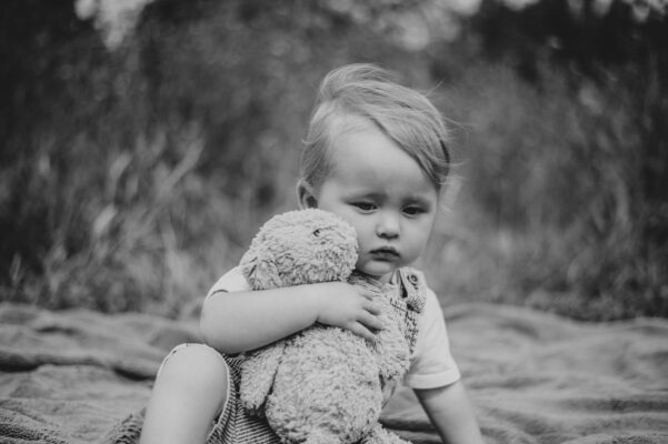 little boy hugs toy rabbit in field Essex family lifestyle childhood baby photographer