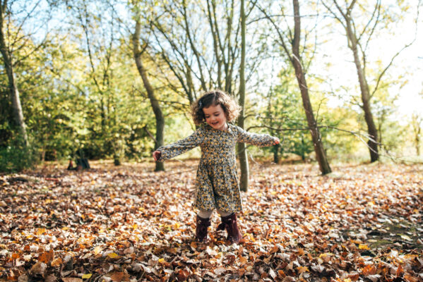 little girl spins in autumn leaves Essex family lifestyle childhood baby photographer