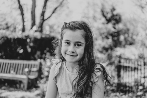 little girl smiles to camera in park Essex family lifestyle childhood baby photographer