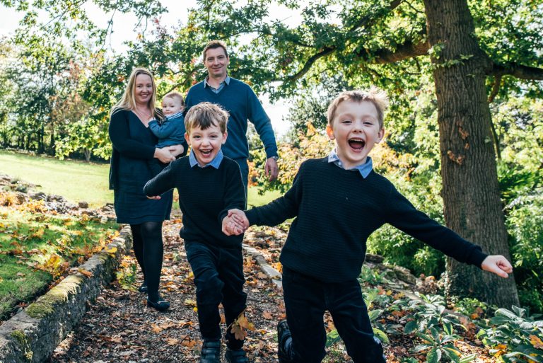 family of five laugh as two boys run towards camera in back garden Essex at home lifestyle family childhood baby photographer