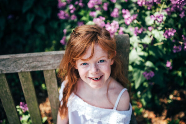 Little girl with red hair laughs as she looks up to the camera Essex lifestyle family childhood baby photographer