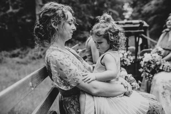 Bridesmaid holds Flower girl on tractor ride to ceremony at Captains Wood Barn