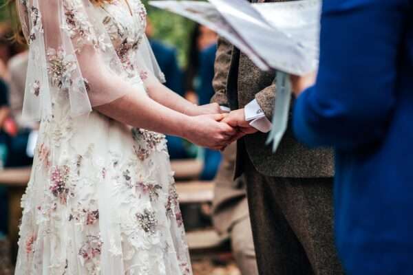 Bride and Groom hold hands during woodland wedding ceremony at Captains Wood Barn