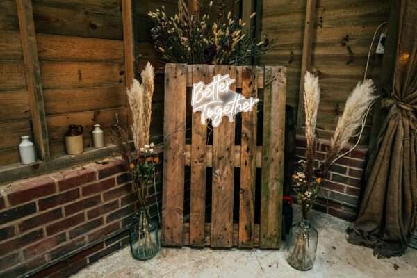 Better Together neon sign on pallet with glass bottles of wild flowers and pampers grass at Captains Wood Barn