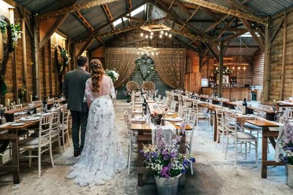 Bride and Groom stand and look at their wedding breakfast barn at Captains Wood Barn