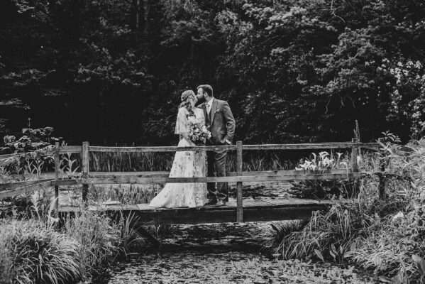 Bride and Groom kiss on bridge at Captains Wood Barn