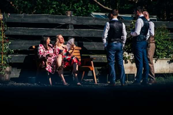 Guests sitting in the sun fan themselves at Captains Wood Barn