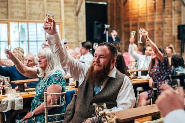 Guests laugh at speeches at Captains Wood Barn Essex documentary wedding photographer