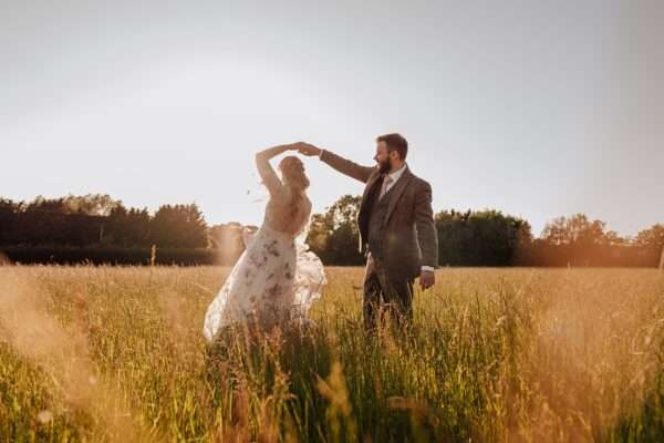 Bride and Groom dance in long grass at sunset at Captains Woods Barn Essex documentary wedding photographer