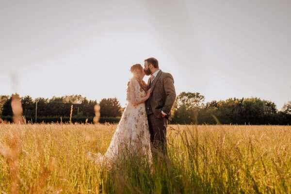 Bride and Groom dance in long grass at sunset at Captains Woods Barn Essex documentary wedding photographer