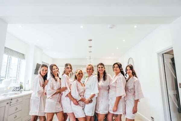 Bride with Bridesmaids in matching dressing gowns at home bridal prep