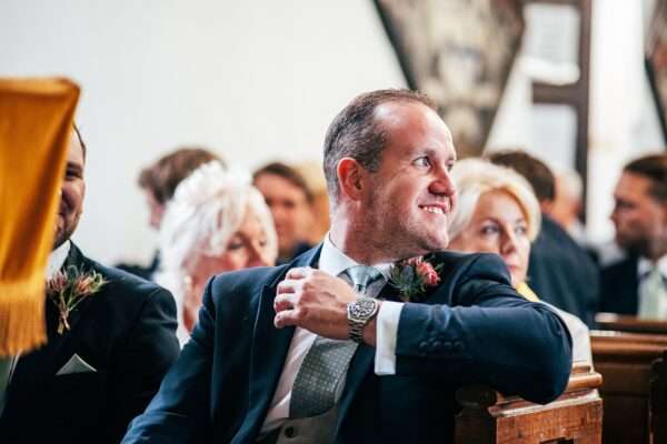 Smiling Groom waits for bride in church