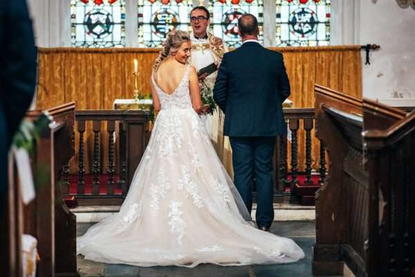 Bride looks back and smiled at guests during wedding ceremony