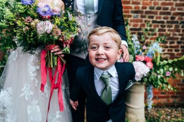 Page boy poses for camera outside Essex church wedding