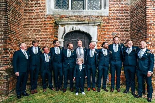 Groom and Groomsmen laugh outside Essex church