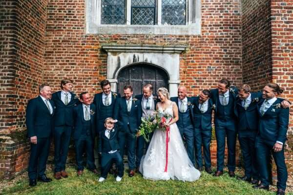 Bride, Groom and Groomsmen laugh outside Essex church