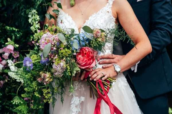 Bride holds summer brights, oversized, trailing, hand tied bouquet by Starry Eyed Events