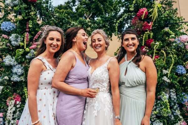 Bride and friends laugh during drinks reception for an Essex back garden tipi wedding