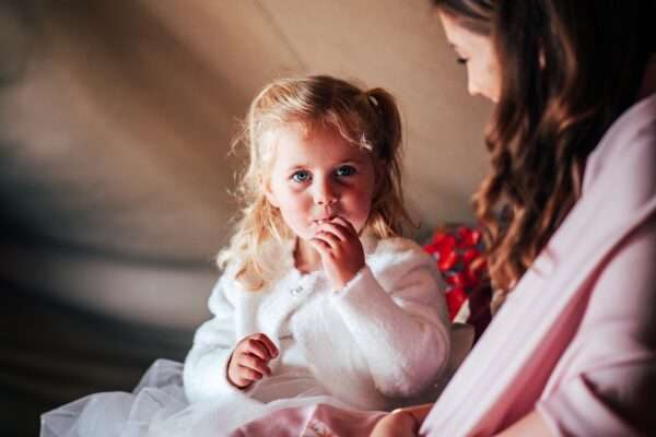 Flower girl eats treat in tipi for an Essex back garden wedding