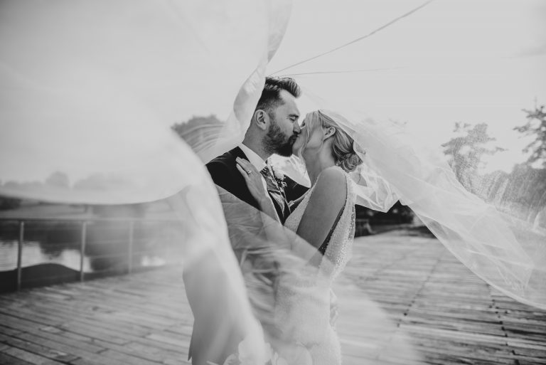 Bride and Groom kiss under billowing veil at Henham Weddings Best Suffolk wedding photographer