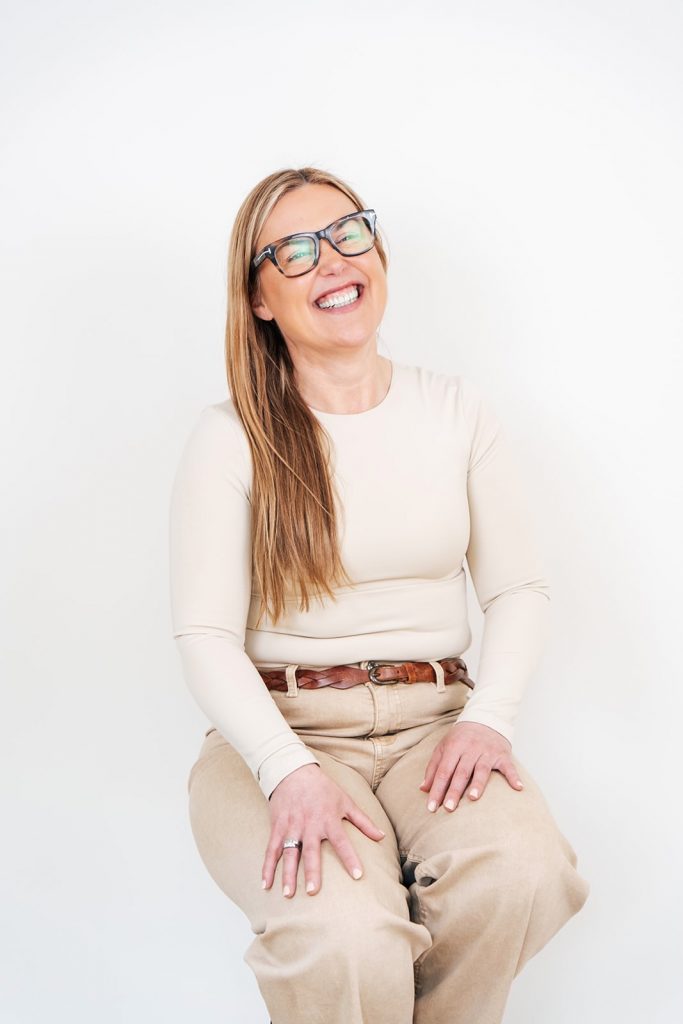 Essex Branding, Content and Head Shot photographer Woman in cream sits on stool and laughs for headshots for aesthetic clinic