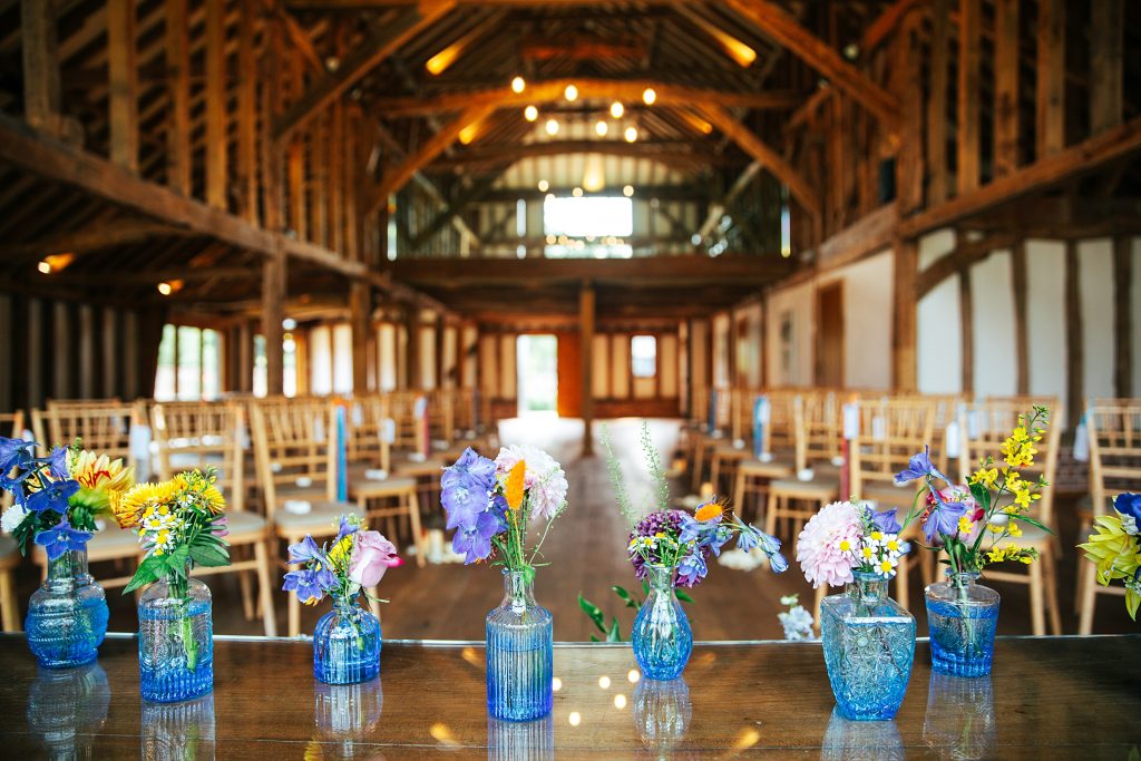 bold colourful flowers in blue glass vases on ceremony table