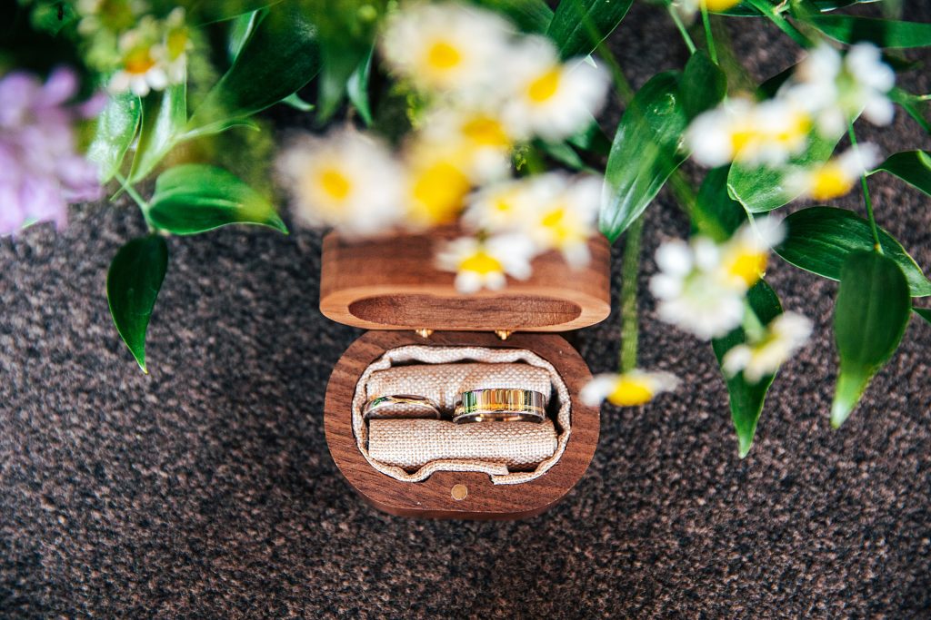 wedding rings in wooden box with flowers in foreground