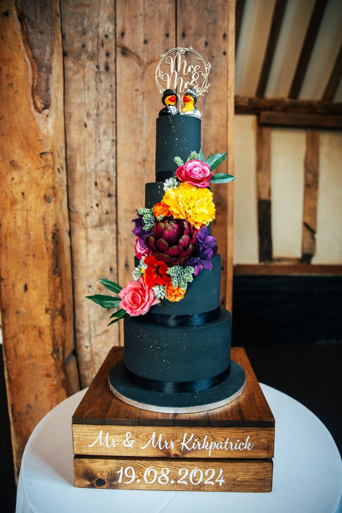 black four tiered wedding cake with bright bold floral decoration