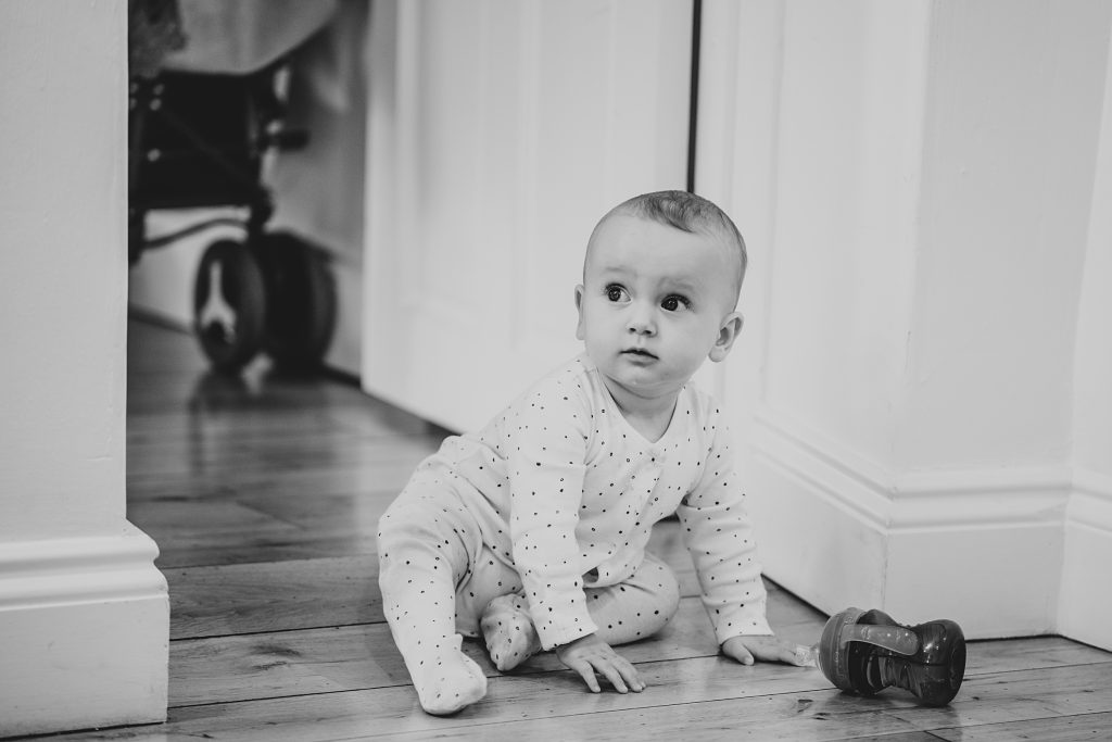 baby in onesie crawls on floor during prep