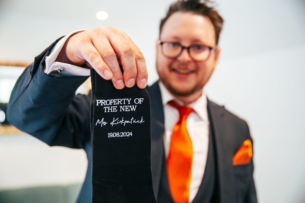groom holds up personalised socks