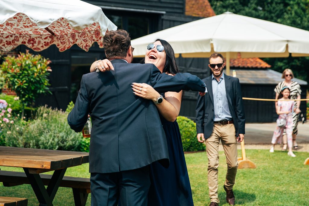 Groom hugs smiling guest