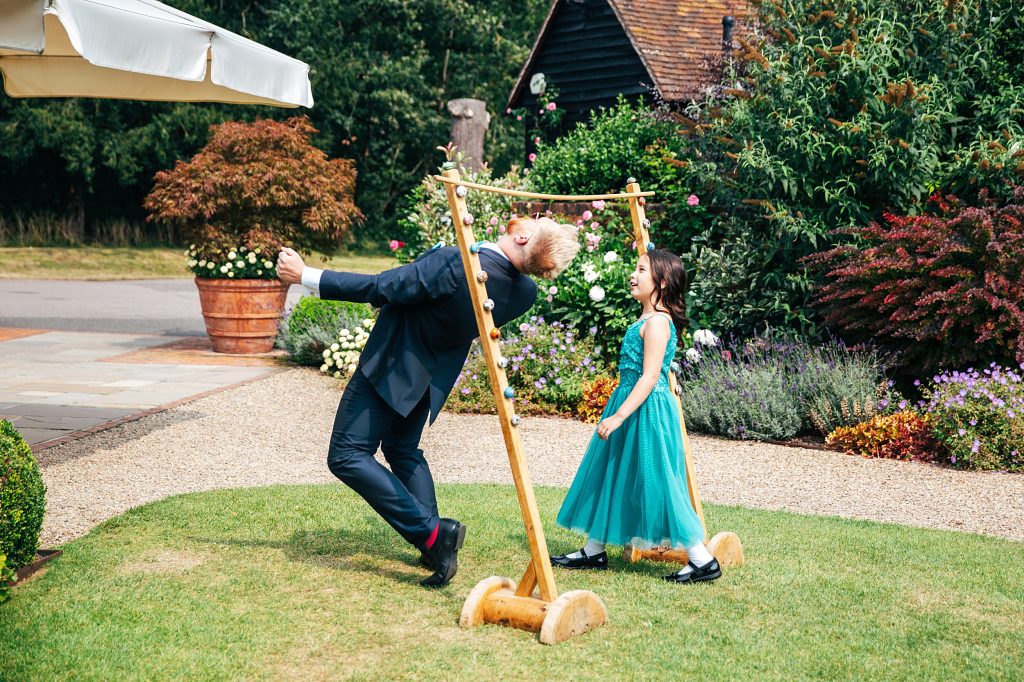 best man and little girl play limbo on lawn