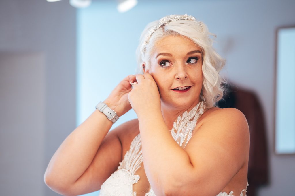 bride puts in earrings in the mirror