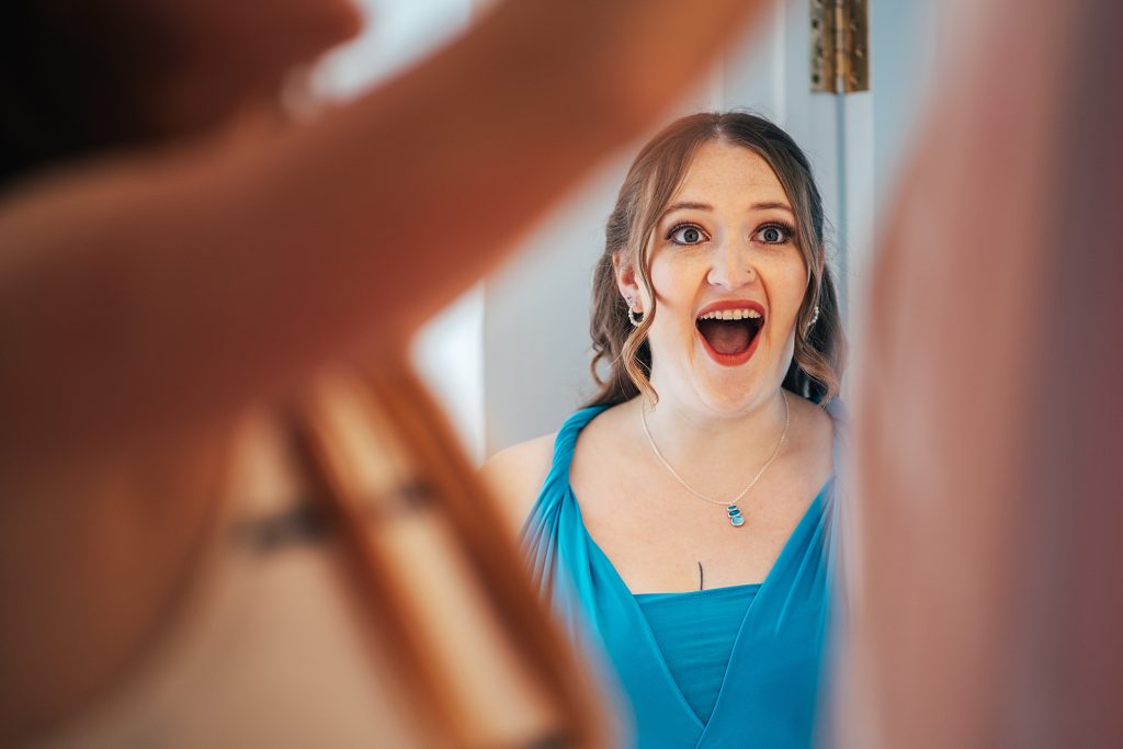 bridesmaid looks open mouthed as she sees bride