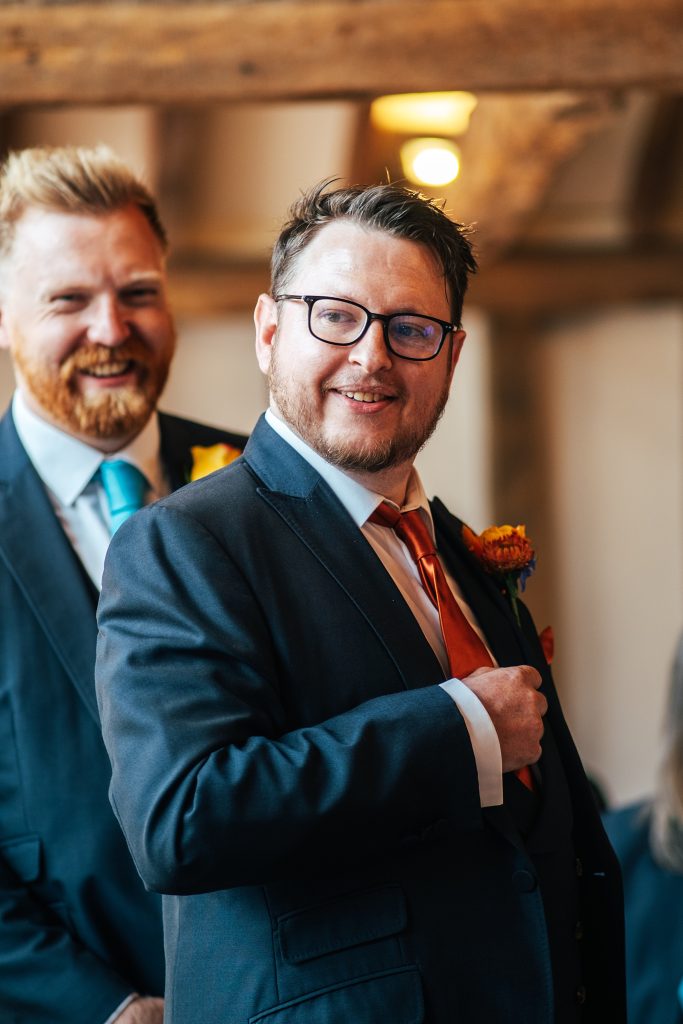 Groom fiddles with tie as he waits for bride