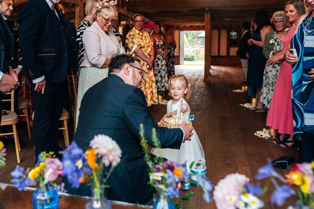 Groom bends down to greet Flower Girl