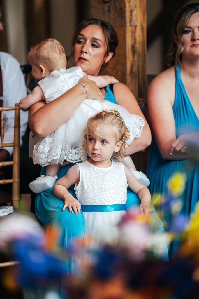 flower girl rests her arms on her mum during ceremony