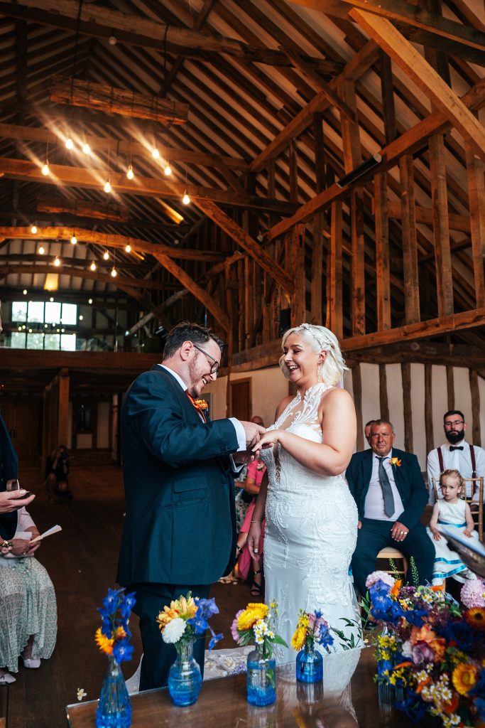 groom laughs as he puts ring on brides finger